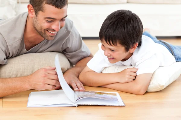 Netter Junge liest ein Buch mit seinem Vater auf dem Fußboden — Stockfoto
