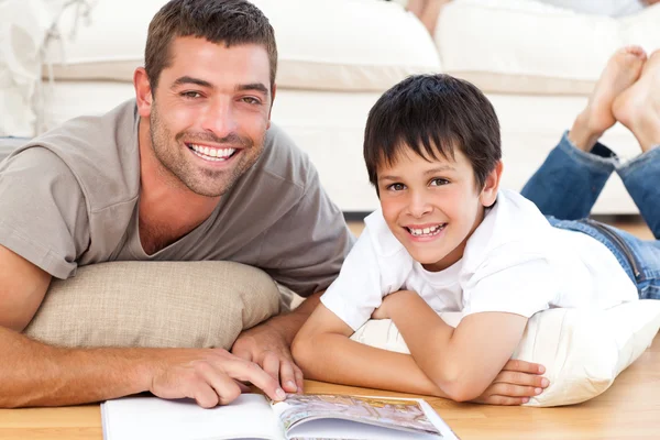 Porträt eines Vaters und seines Sohnes beim gemeinsamen Lesen eines Buches auf dem Flur — Stockfoto