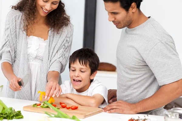 Lycklig familj förbereder en sallad tillsammans i köket — Stockfoto