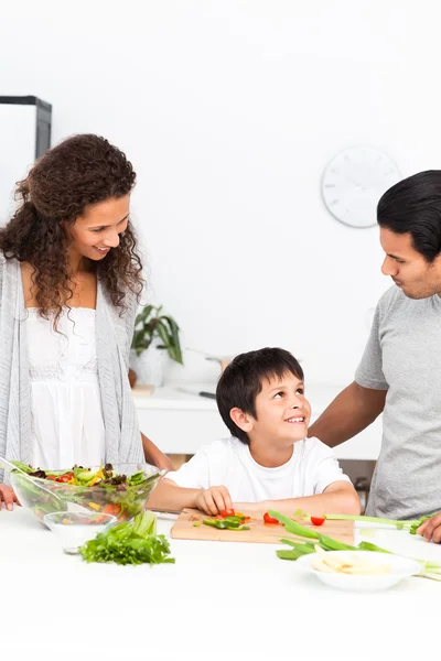 Família feliz cortando legumes juntos na cozinha — Fotografia de Stock
