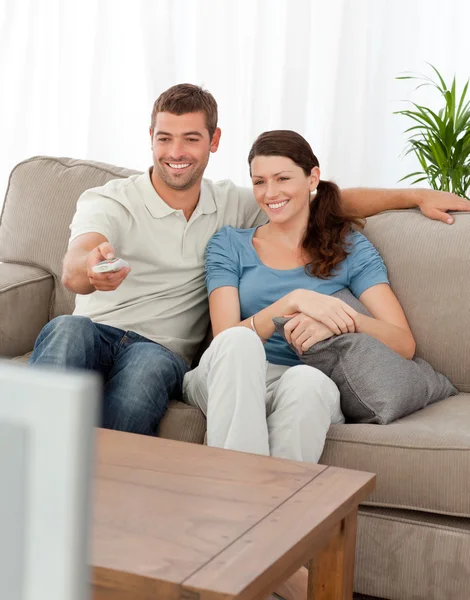Homem feliz mudando de canal enquanto assiste televisão com seu wi — Fotografia de Stock
