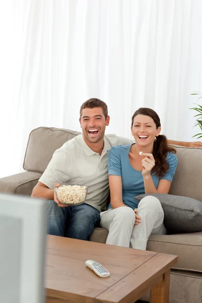 Bonito casal comer milho pop enquanto assiste televisão na areia — Fotografia de Stock