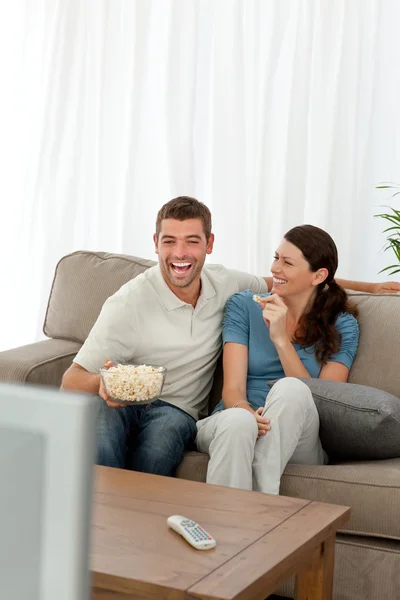 Casal alegre comendo milho pop enquanto assiste a um filme em quadrinhos — Fotografia de Stock