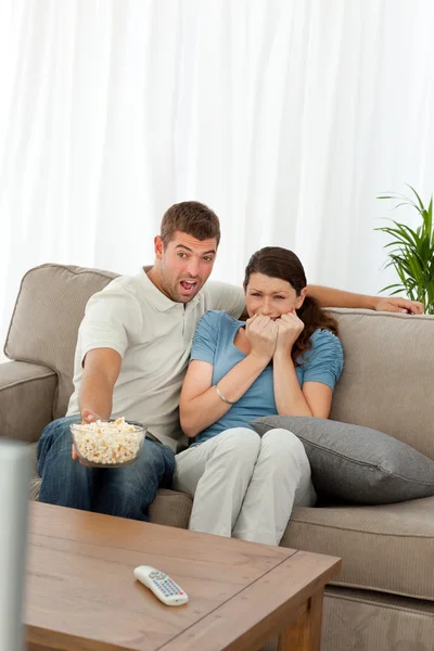 Livrädd par tittar på en skräckfilm i vardagsrummet — Stockfoto