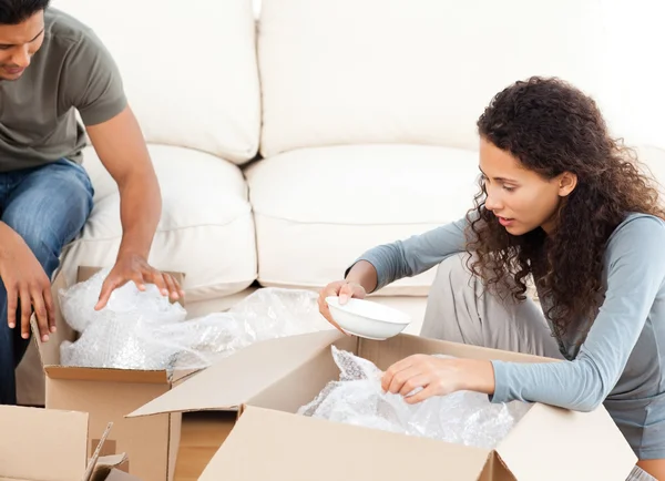 Happy woman packing glasses with her husband in the living-room — Stock Photo, Image
