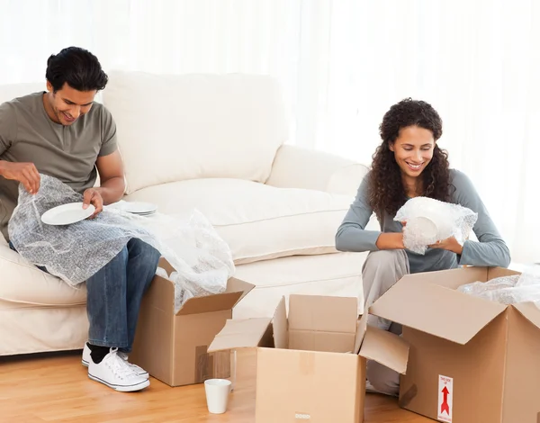 Joyful couple packing glasses together in the living room — Stock Photo, Image