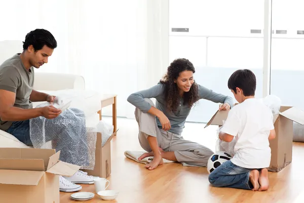 Feliz família embalando pratos juntos em sua sala de estar — Fotografia de Stock