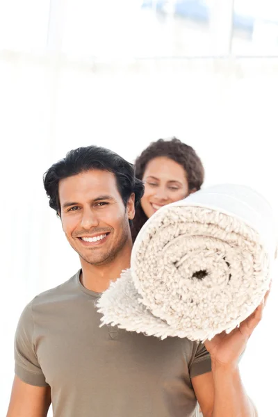 Casal hispânico carregando um tapete de pé na sala de estar — Fotografia de Stock