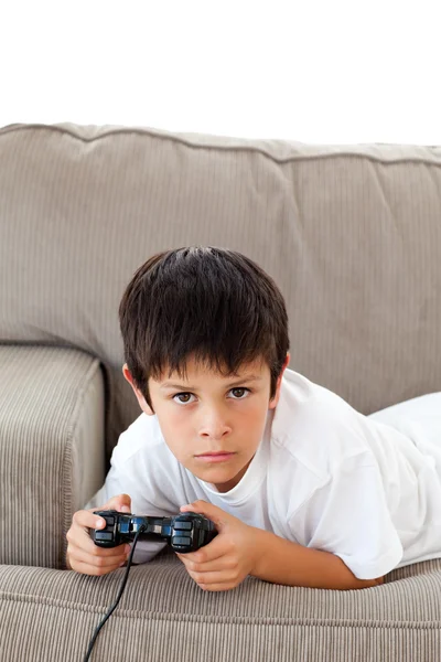 Menino concentrado jogando videogames deitado no sofá — Fotografia de Stock