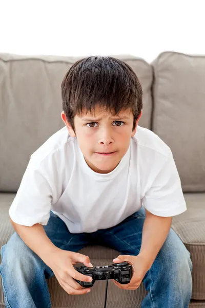 Симпатичный мальчик играет в видеоигры, сидя на диване — стоковое фото