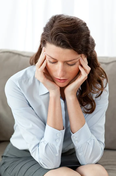 Güzel iş kadını kanepede oturan bir baş ağrısı olması — Stok fotoğraf