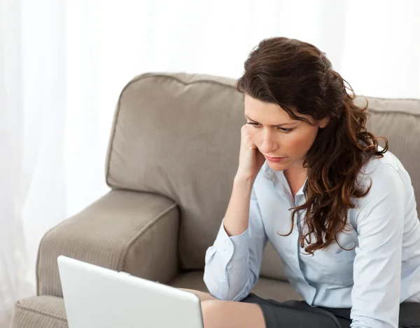Donna d'affari seria che lavora sul suo computer portatile sul divano — Foto Stock