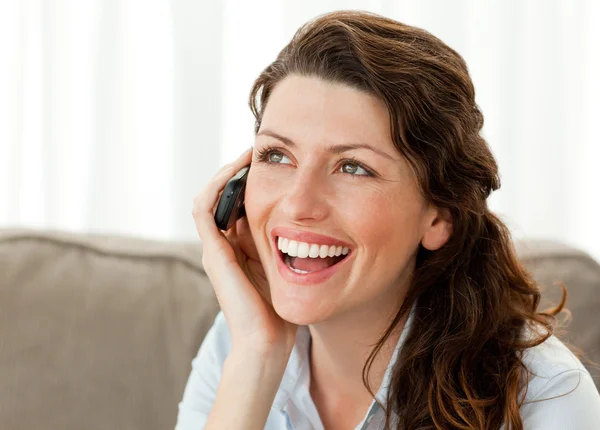 Радостная женщина по телефону сидит на диване — стоковое фото