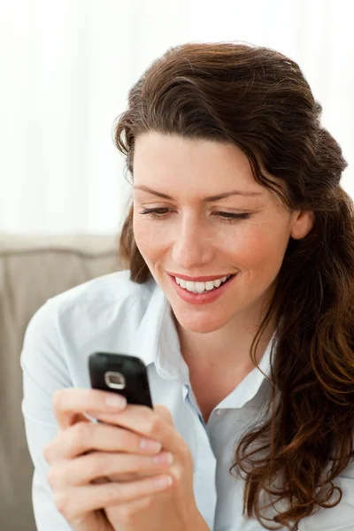 Mulher bonita enviando uma mensagem de texto sentado no sofá — Fotografia de Stock