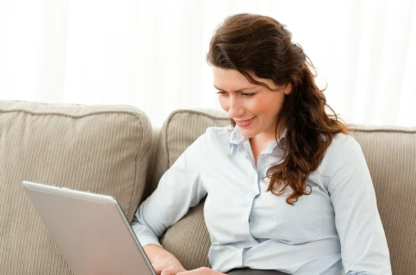 Empresária feliz trabalhando em seu laptop sentado no sofá — Fotografia de Stock
