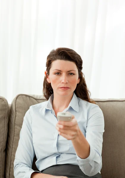 Charismatická žena držící vzdálené sedí na pohovce — Stock fotografie