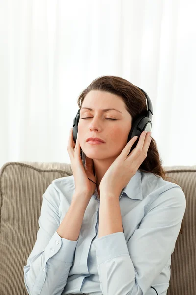 Концентрована жінка слухає музику на дивані — стокове фото