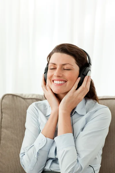 陽気な女性実業家、ソファーで音楽を聴く — ストック写真