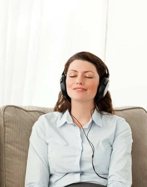 Uvolněná žena poslech hudby se sluchátky v obývacím pokoji — Stock fotografie