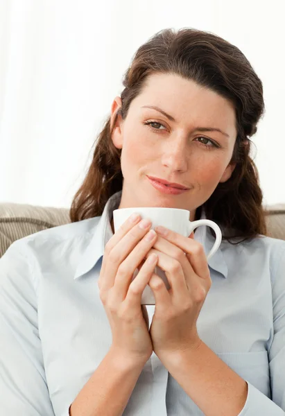 Kanepede oturmuş kahve tutan güzel kadın — Stok fotoğraf