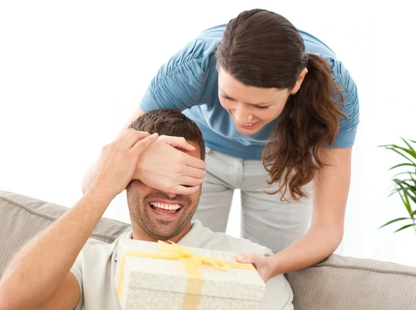 Happy woman giving a present to her husband in the living room — Stock Photo, Image