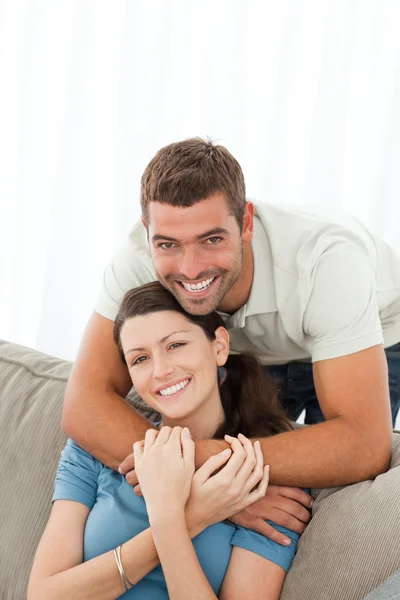 快乐拥抱他的女友坐在沙发上的男人 — 图库照片