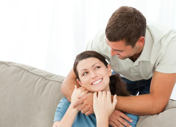 Handsome man hugging his wife while resting on the sofa — Stock Photo, Image
