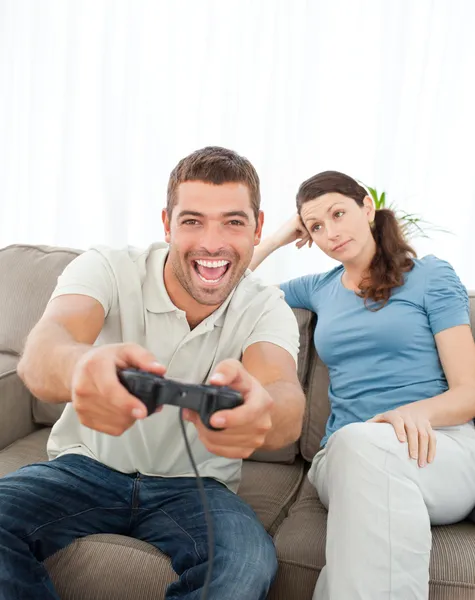 Mujer aburrida mirando a su novio jugando videojuegos en el s —  Fotos de Stock