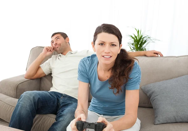 Серьезная женщина, играющая в видеоигры, пока ее парень ждет — стоковое фото