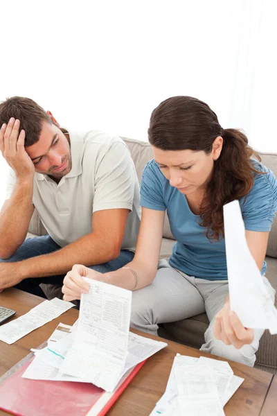Stressad man och kvinna som tittar på sina räkningar i vardagsrummet — Stockfoto