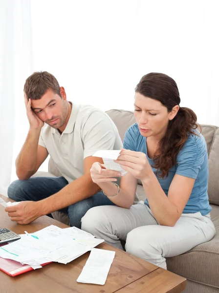Stressed couple doing their accounts sitting on the sofa — Stock Photo, Image