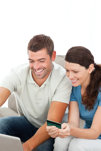 Счастливая пара покупает онлайн вместе сидя на диване — стоковое фото