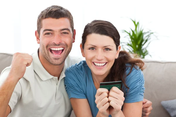 소파에 자신의 신용 카드를 들고 행복 한 커플의 초상화 — 스톡 사진