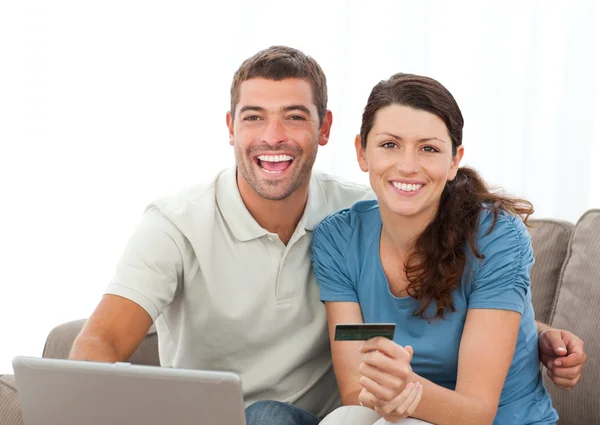 Casal bonito com seu laptop e cartão de crédito sentado na liv — Fotografia de Stock