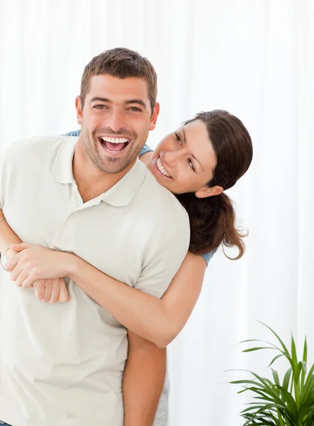 Veselá žena objímala svého manžela, stojící v obývacím pokoji — Stock fotografie