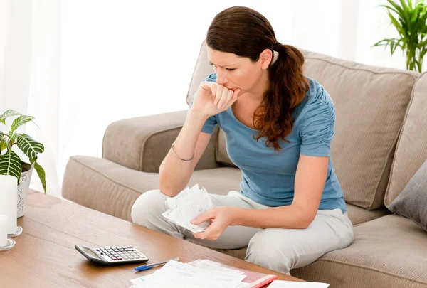 Mulher estressada calculando suas contas sentada no sofá — Fotografia de Stock