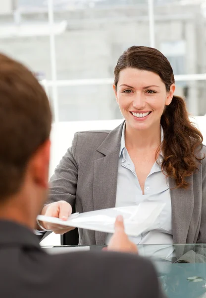 Glad affärskvinna ger ett papper till en manlig kollega under en — Stockfoto