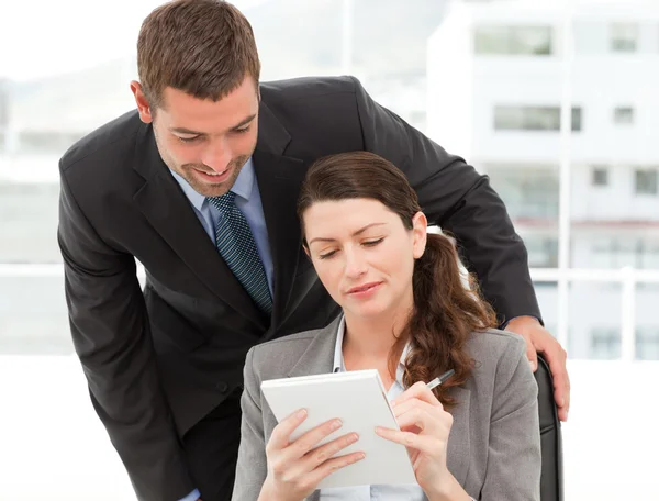 Happy businessman helping a businesswoman working at her desk — Stock Photo, Image