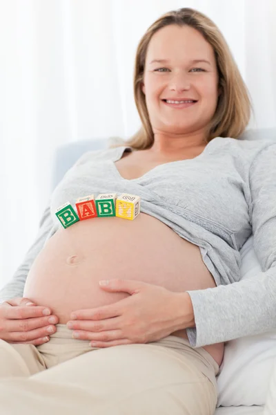 Симпатична вагітна жінка з дитячими літерами на животі — стокове фото
