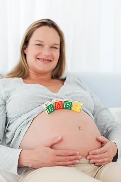 Niedliche schwangere Frau mit Babybuchstaben auf dem Bauch — Stockfoto