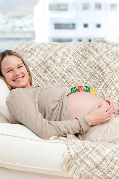 Hübsche zukünftige Mutter mit Babybuchstaben auf dem Bauch — Stockfoto
