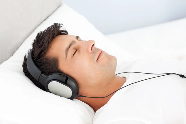 Мирный человек расслабляется, слушая музыку на кровати — стоковое фото