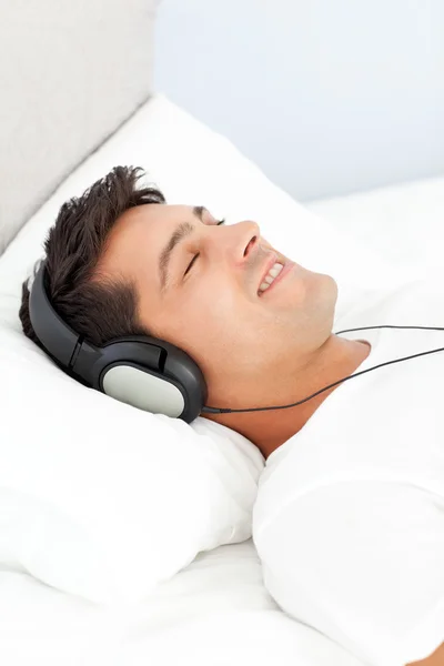 Homem tranquilo relaxando ouvindo música em sua cama — Fotografia de Stock