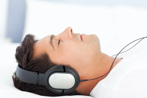 Uomo tranquillo rilassante ascoltando musica sul suo letto — Foto Stock