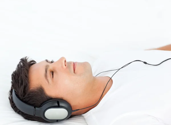 Peaceful man relaxing by listening music on his bed — Stock Photo, Image