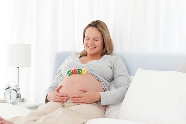 Портрет беременной женщины с письмами мамы на животе — стоковое фото