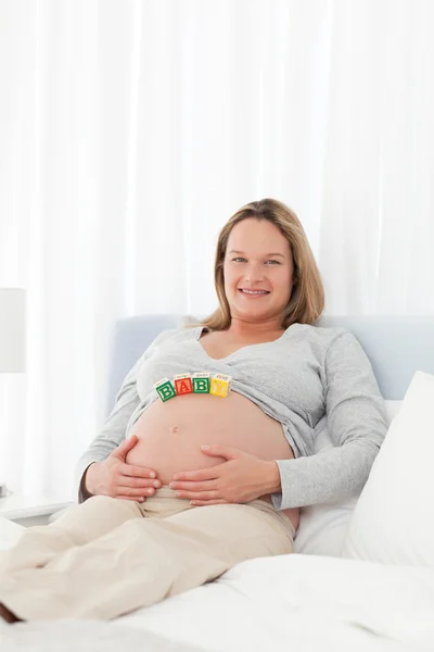 一个怀孕的女人，在她的肚子上有妈妈字母的肖像 — 图库照片