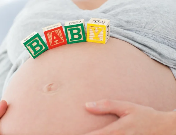 Κοντινό πλάνο μια έγκυος γυναίκα με μωρό γράμματα την κοιλίτσα της — Φωτογραφία Αρχείου
