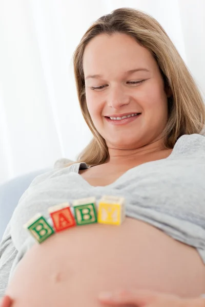 Mujer embarazada alegre con letras de bebé en su vientre —  Fotos de Stock
