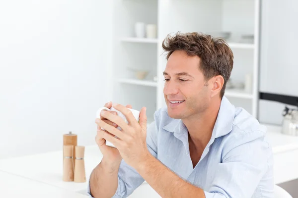 Attractive man drinking coffee sitting at a table — Stock Photo, Image